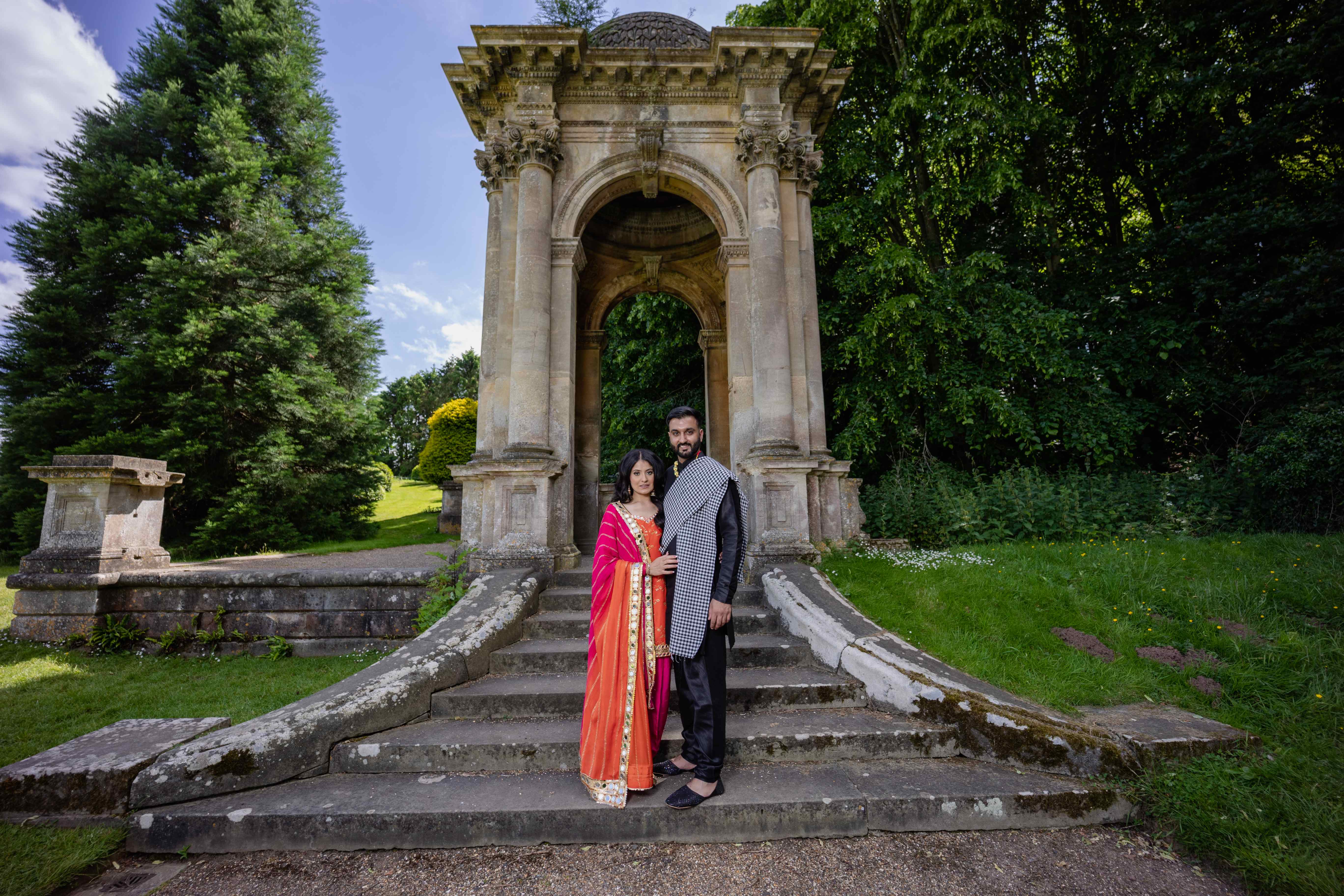 Couple in traditional attire at stone garden pavilion