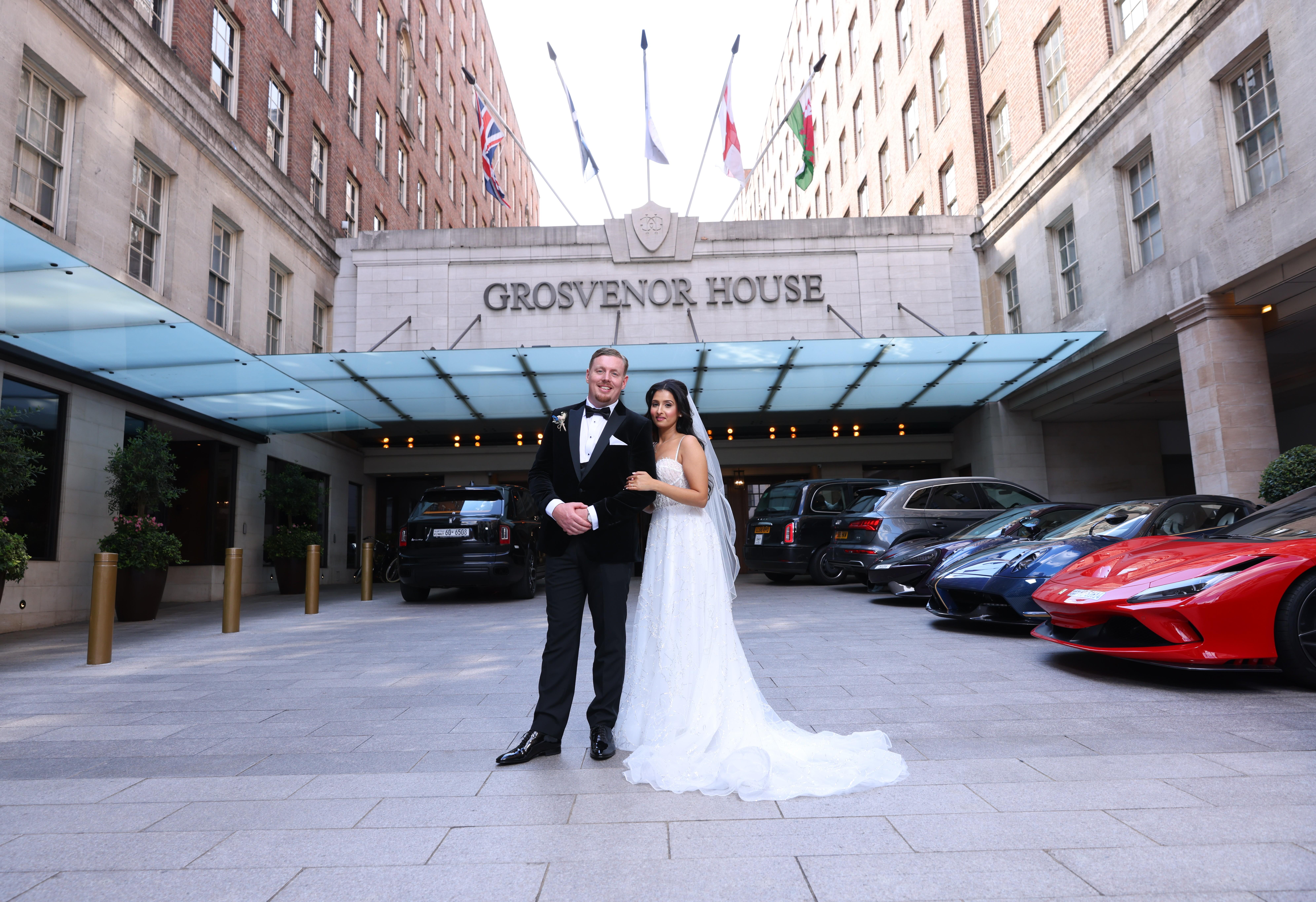 Bride and groom at Grosvenor House with luxury cars